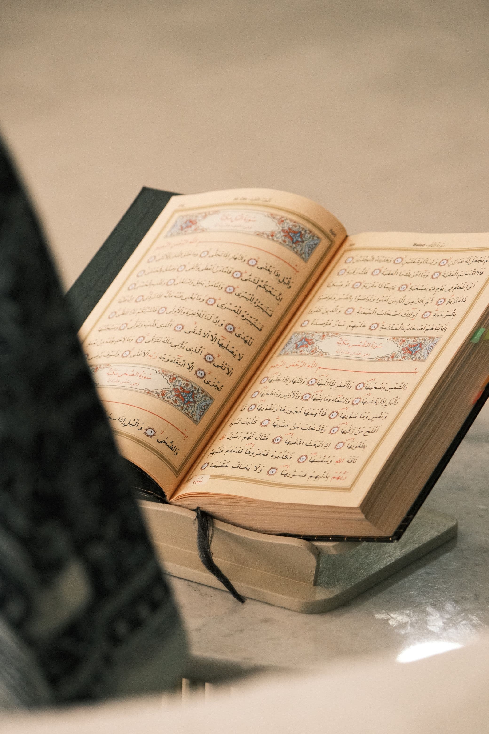 Open Quran on a wooden stand while a teacher points to the text